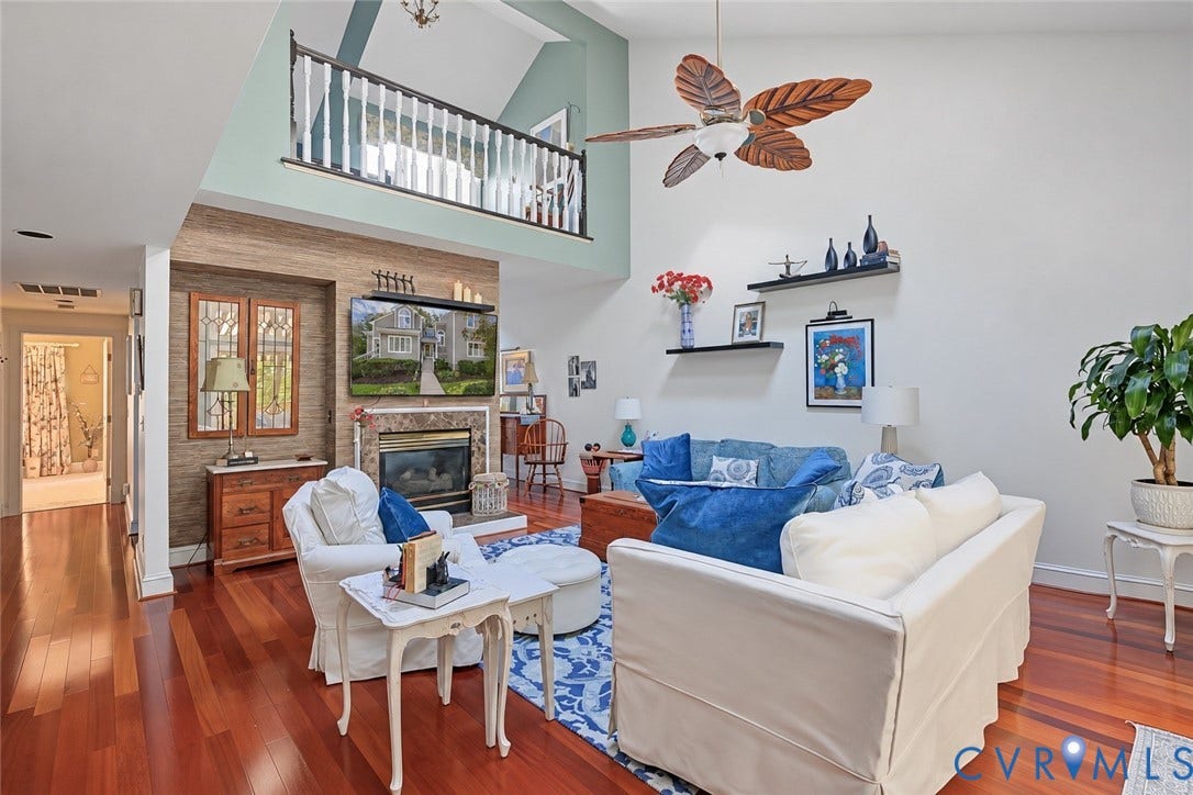 3131 Stony Point Road, #B, Richmond, VA 23235 Hardwood flooring, two-story living area, fireplace with marble-look surround, balcony with wood railing, and vaulted ceiling with ceiling fan