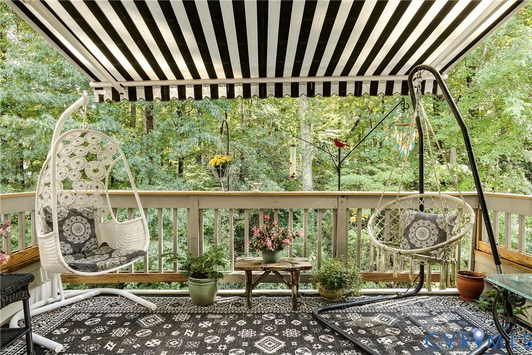3131 Stony Point Road, #B, Richmond, VA 23235 Deck featuring a black and white striped retractable awning, wooden railing, and patterned outdoor flooring