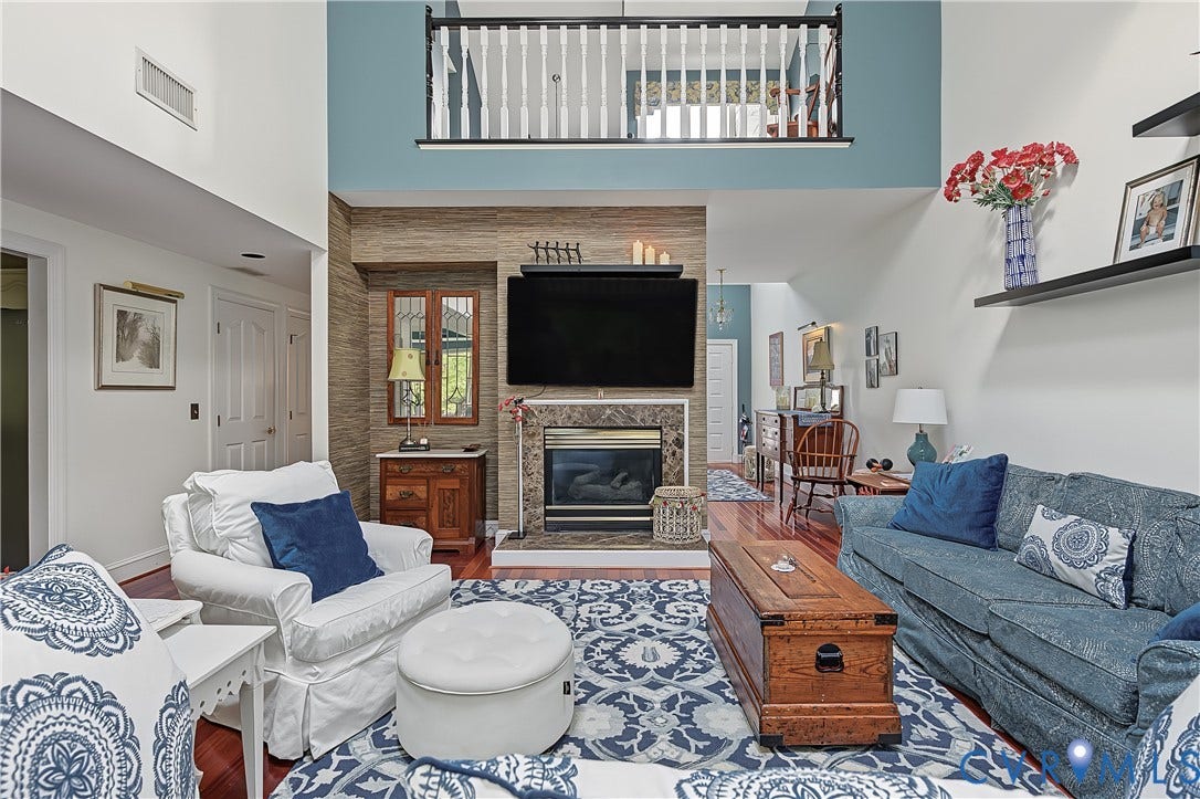 3131 Stony Point Road, #B, Richmond, VA 23235 Double-height ceiling, fireplace with stone surround, wood-finish flooring, upper-level railing, and built-in shelving