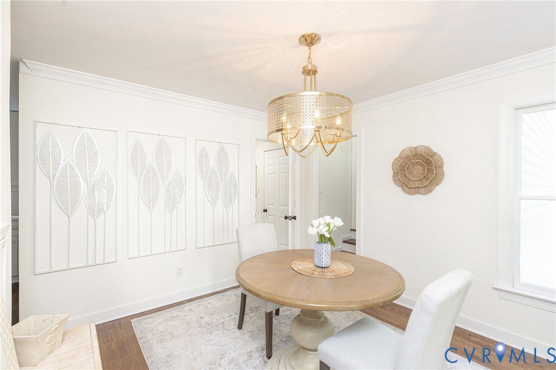 Wood-finish flooring, crown molding, and a gold-tone chandelier with a perforated drum shade