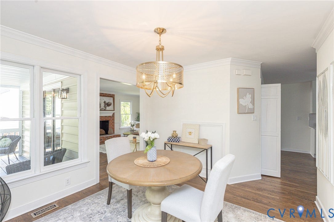 Warm wood-finish flooring, white trim details, and a decorative gold-tone chandelier