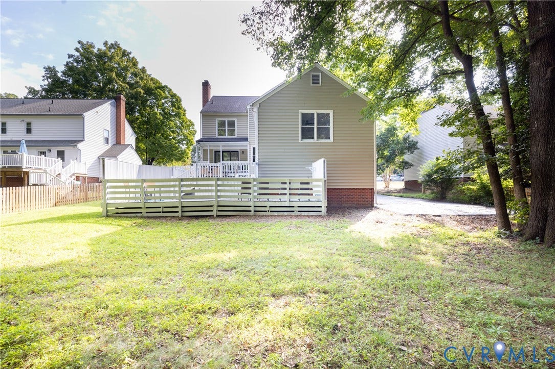 Expansive backyard with a manicured lawn, multi-level deck, and mature trees