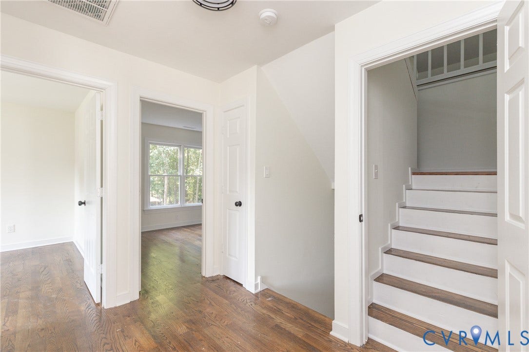 Hardwood flooring, painted interior doors, staircase with wood treads, ceiling-mounted light fixture, and white trim throughout