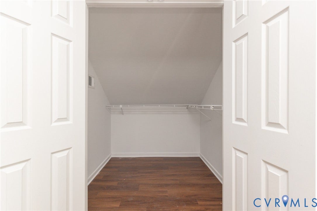 White paneled doors opening to a storage area with wood-finish flooring and a white wire shelving system