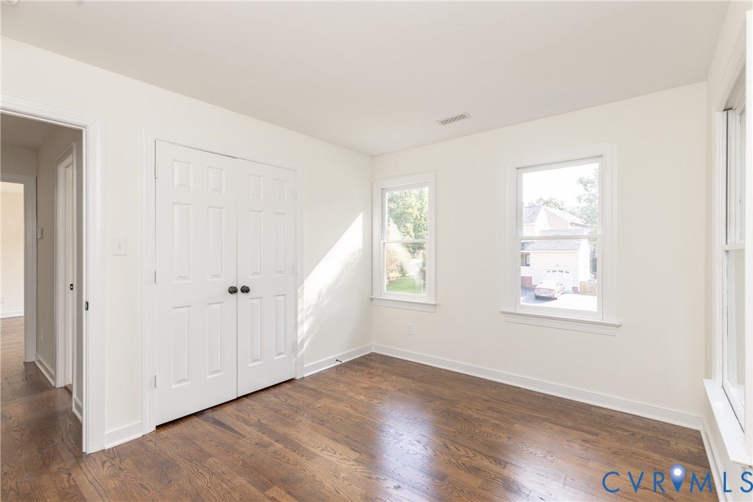 Hardwood flooring throughout, multiple windows, white paneled bifold closet doors, and a neutral color palette