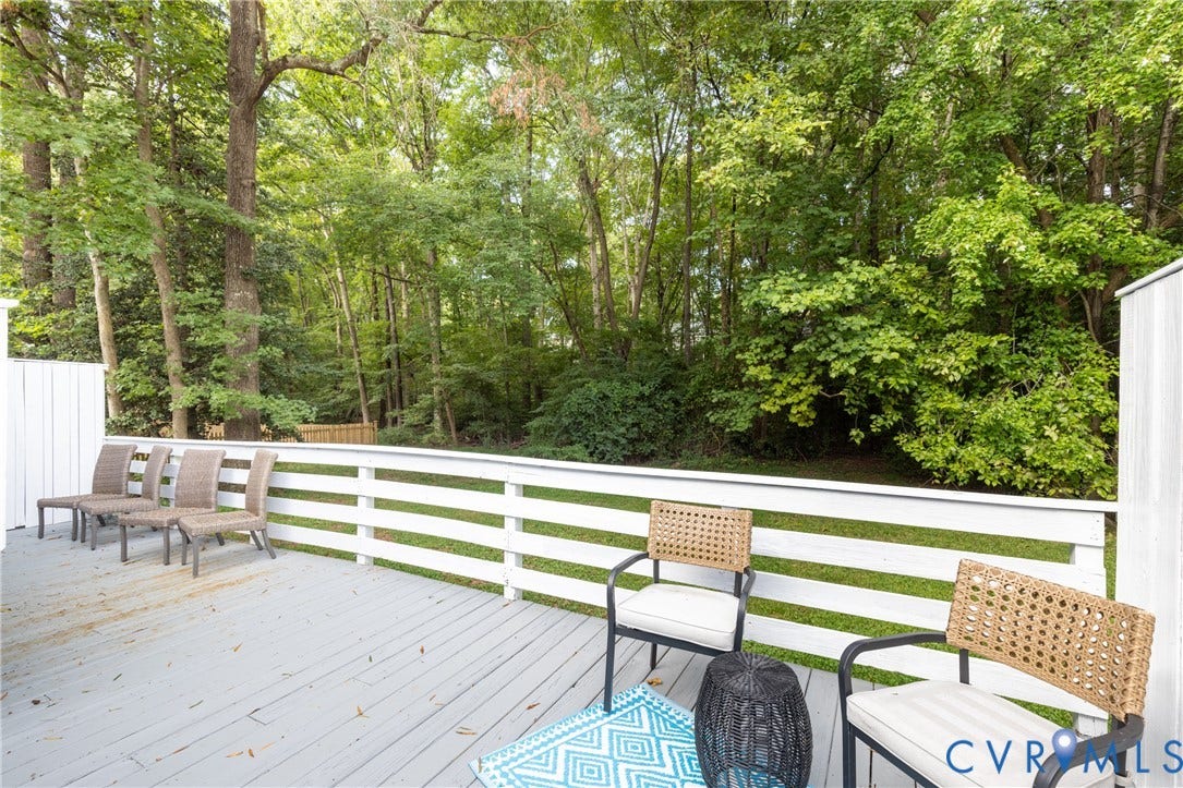 Deck with a white horizontal slat railing, wood-finish flooring, and a treed backdrop