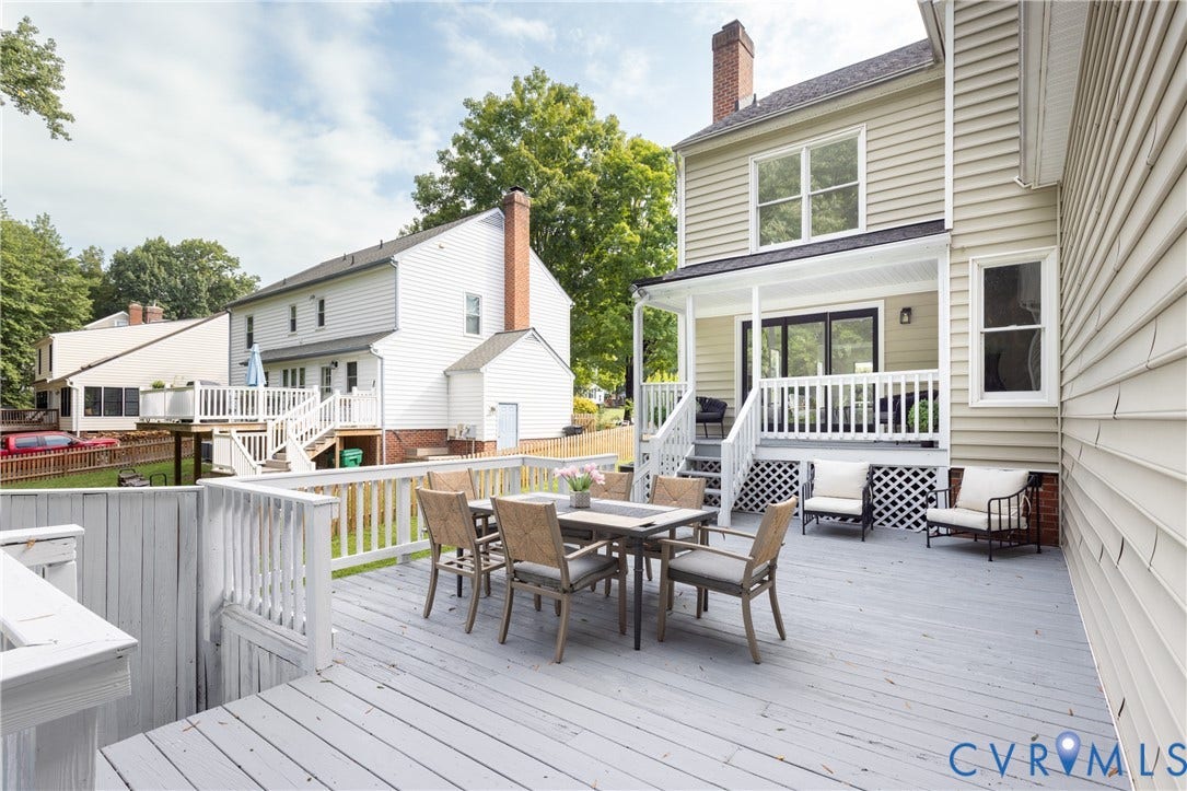 Expansive multi-level wood deck, covered porch with white railing, sliding glass door access, and lattice skirting