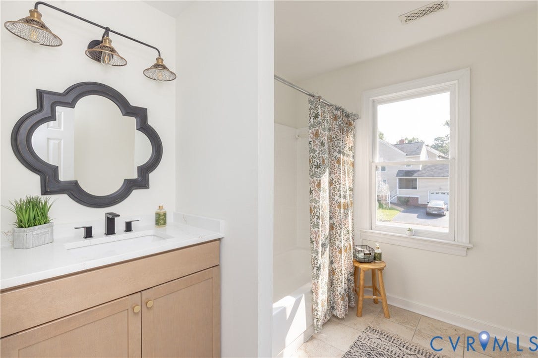 Single vanity with a white countertop and integrated sink, matte black faucet, and a decorative mirror