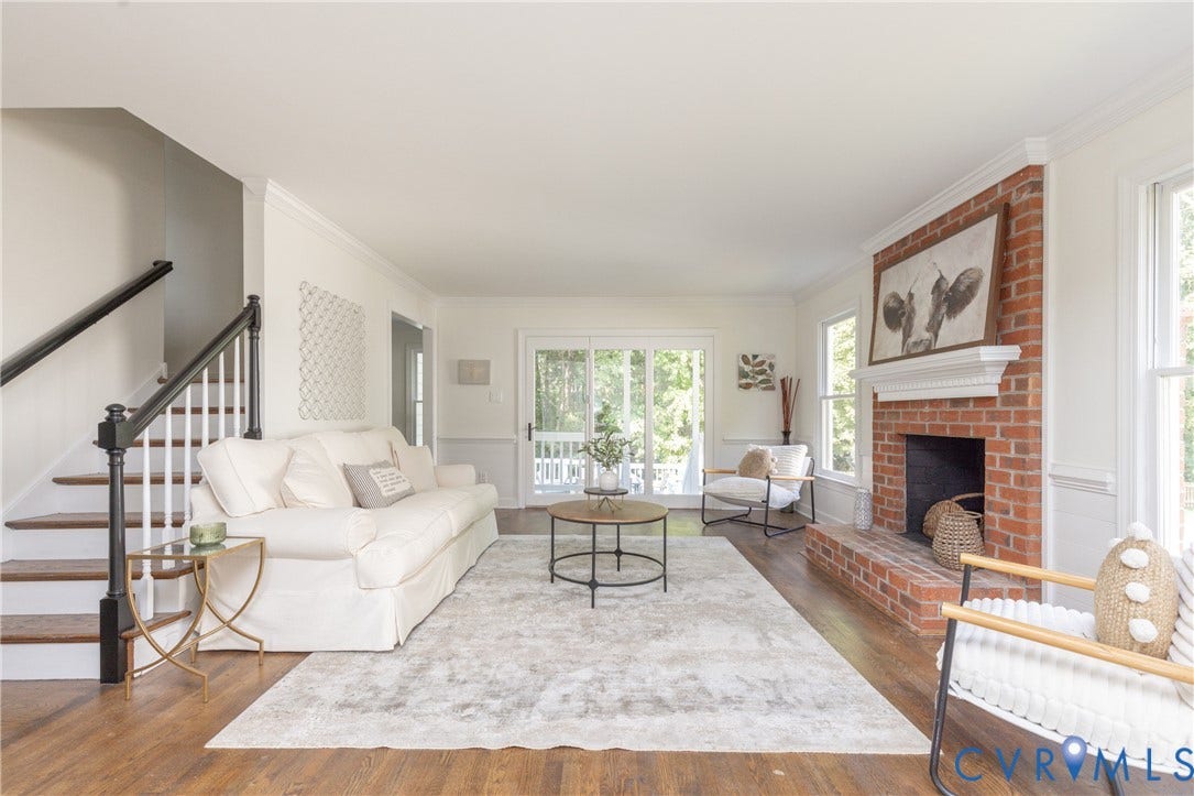 Hardwood-finish flooring, brick fireplace with mantel, white trim, sliding glass door to exterior, and staircase with dark wood handrail