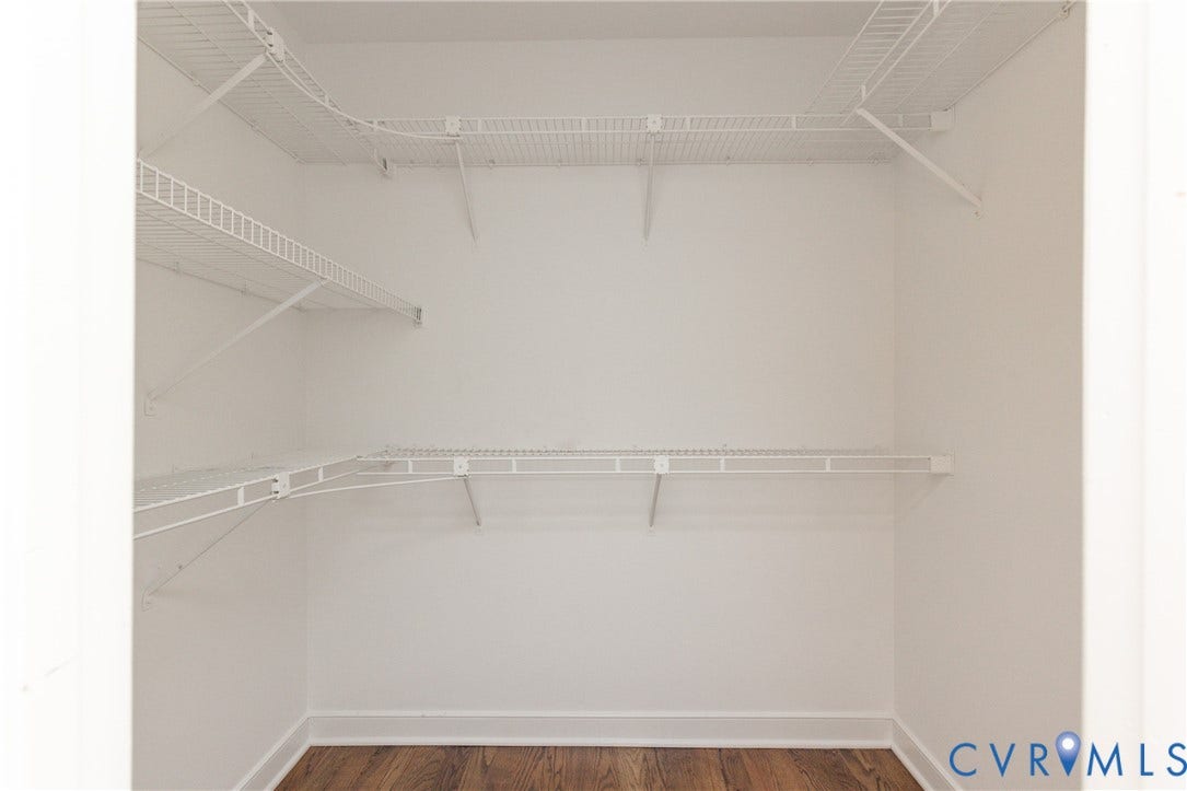Walk-in closet with multi-level wire shelving and wood-finish flooring