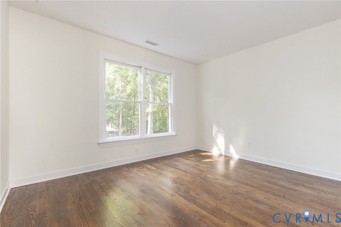Hardwood flooring, white walls, and a large window with white trim