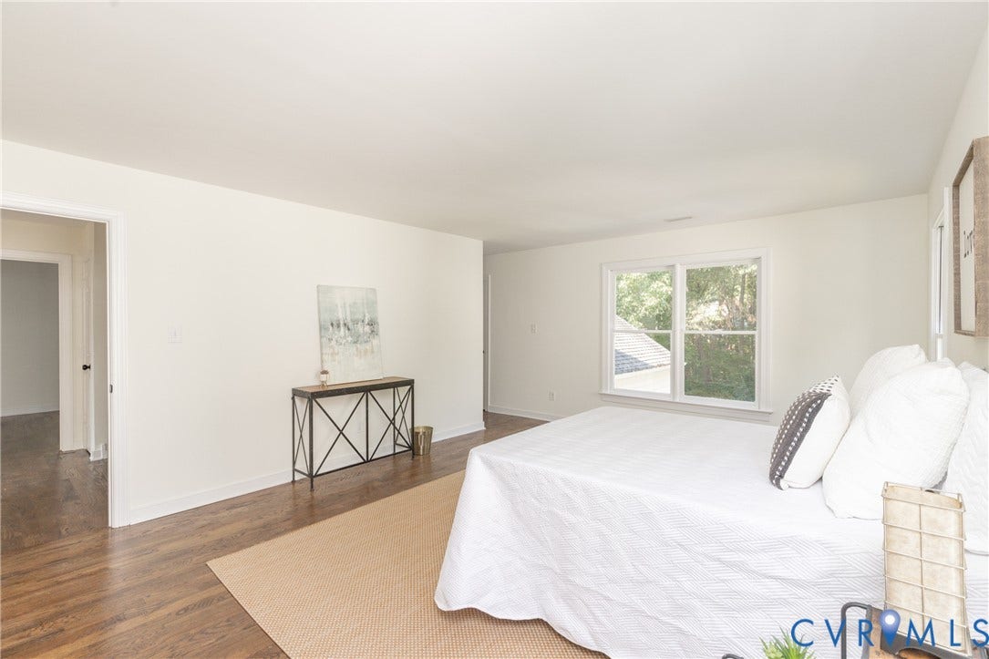 Wood-finish flooring, white painted walls, and a large window with white trim
