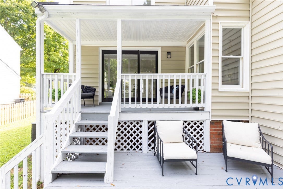 Covered porch with white railings, lattice skirt, and steps to a lower deck area