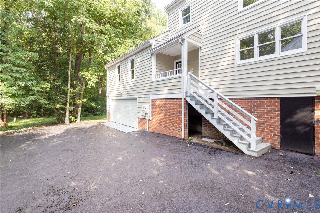 Exterior featuring light-colored horizontal siding, a two-car garage, brick foundation, and a covered porch with white railings