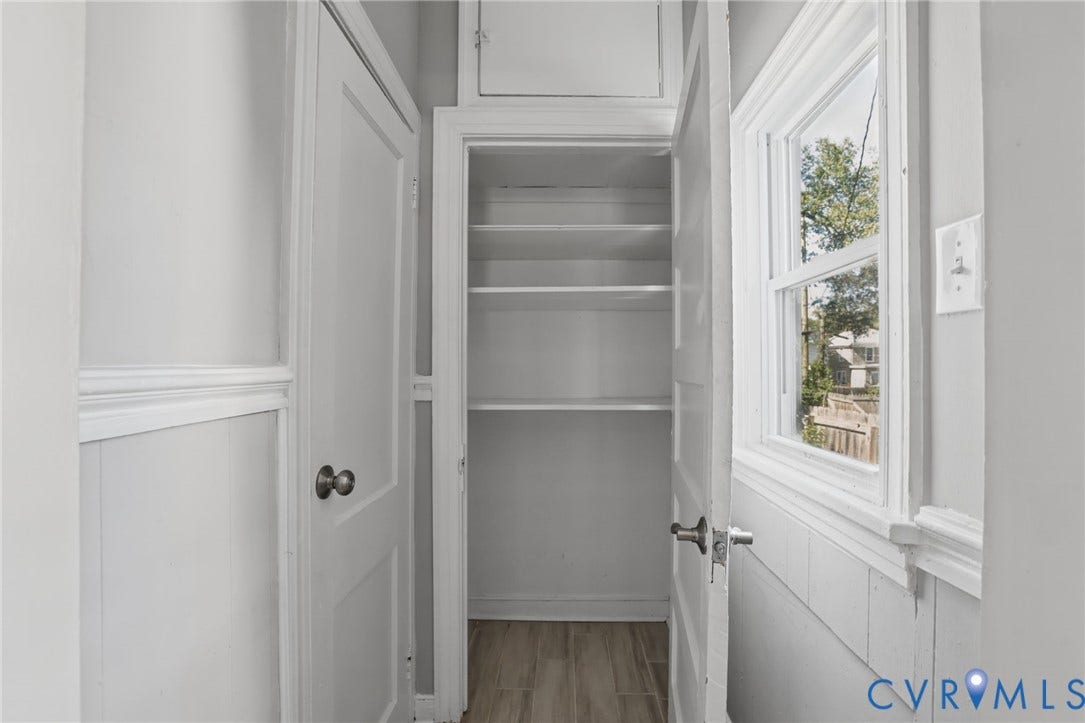 Built-in shelving, paneled walls, window with trim, and wood-finish flooring