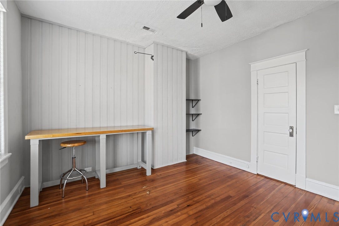 Hardwood flooring, paneled interior door, ceiling fan, built-in shelving, and vertical plank wall accent