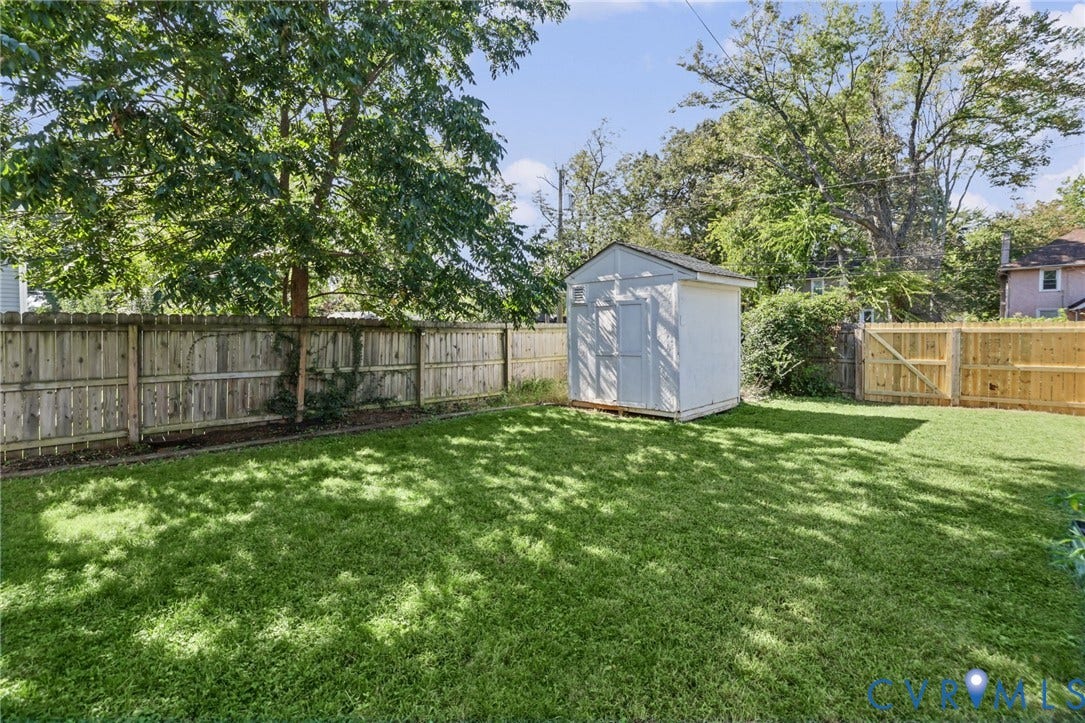 Expansive green lawn with a storage shed, mature trees, and wood fencing