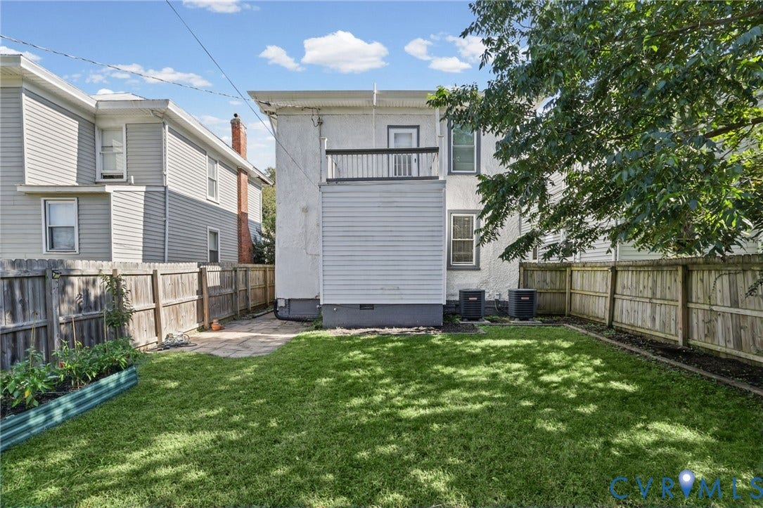 Expansive backyard featuring a manicured lawn, full perimeter fencing, and a raised garden bed