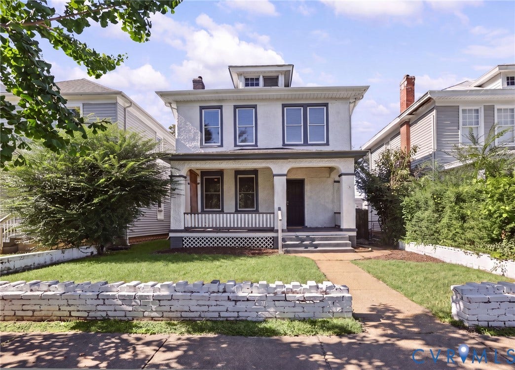 Two-story stucco exterior with a dormer, covered front porch, and a brick accent wall