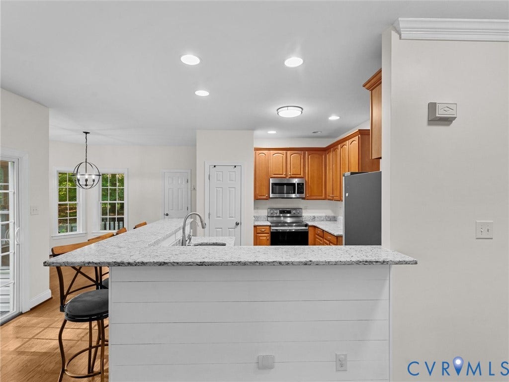 Kitchen featuring a breakfast bar with stone-finish countertop, wood-finish cabinetry, stainless steel appliances, and recessed lighting