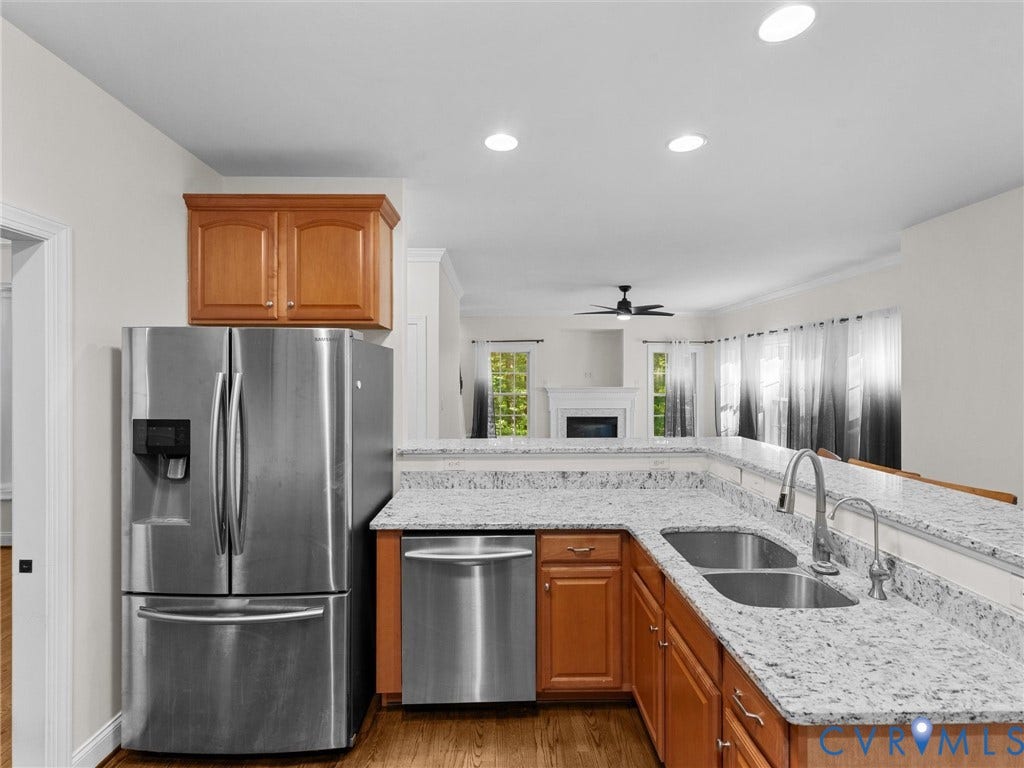 Kitchen featuring granite countertops, stainless steel appliances, wood cabinetry, and a double basin sink