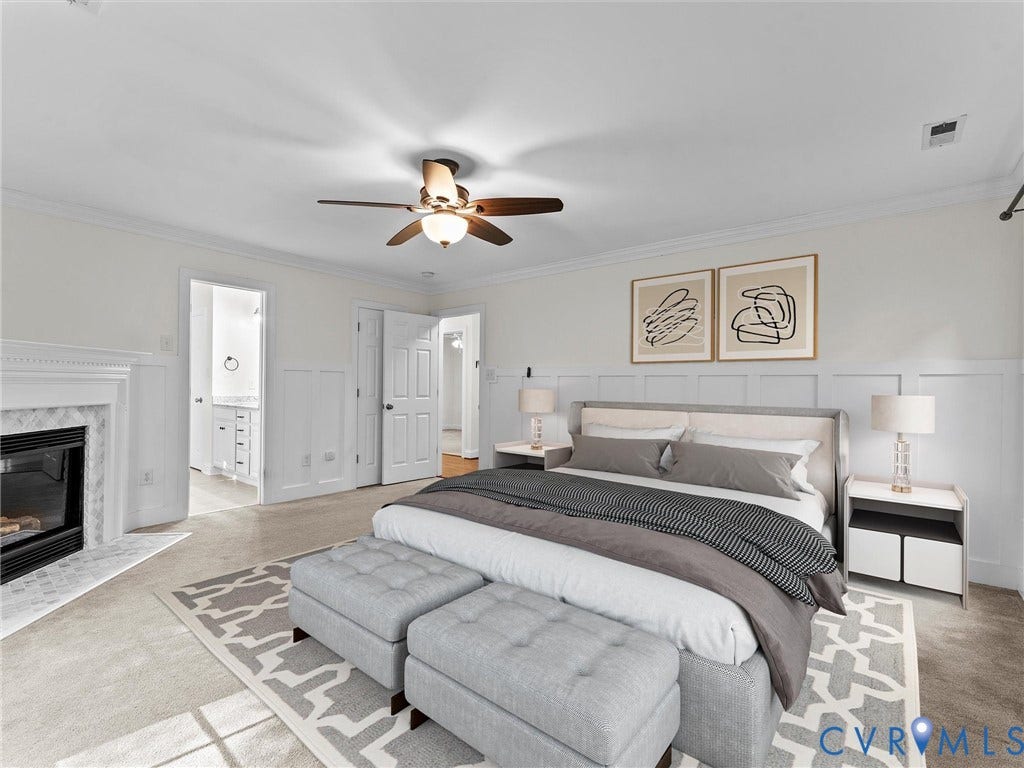 Recessed fireplace with a tiled surround, crown molding, ceiling fan, and carpeted flooring