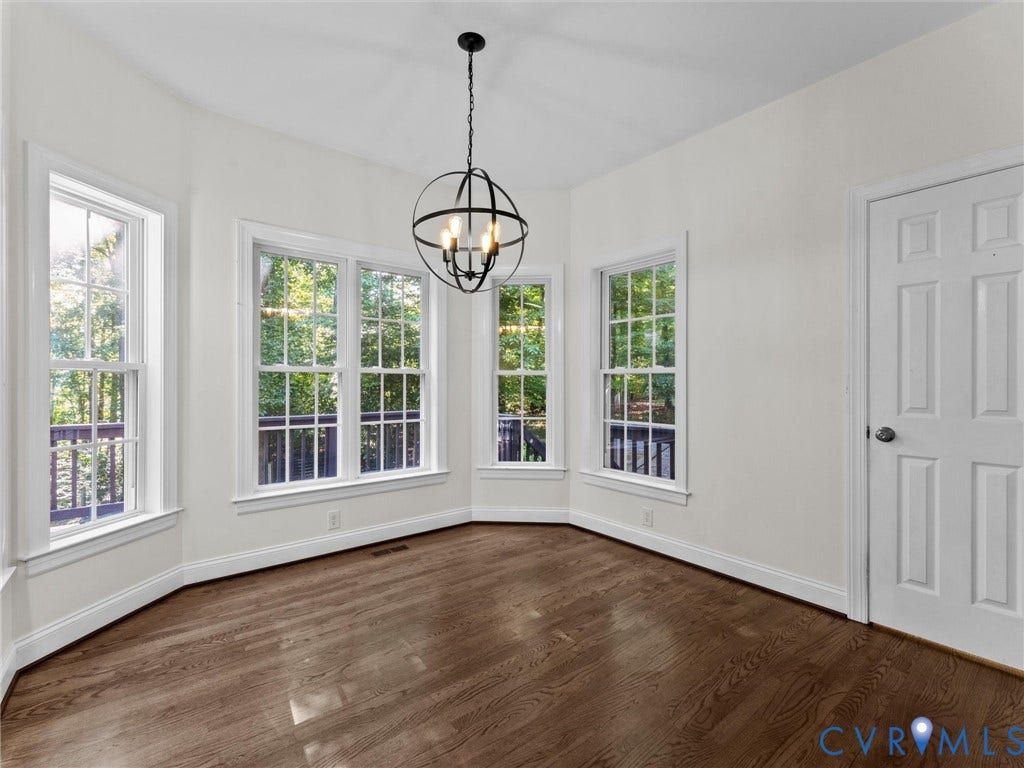 Bay window with multiple double-hung windows, wood-finish flooring, and a modern spherical chandelier