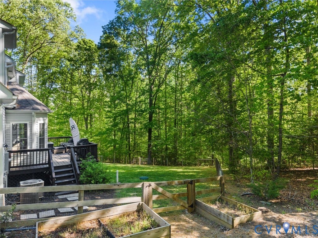 Expansive backyard with a wooden fence, raised garden beds, and a multi-level deck