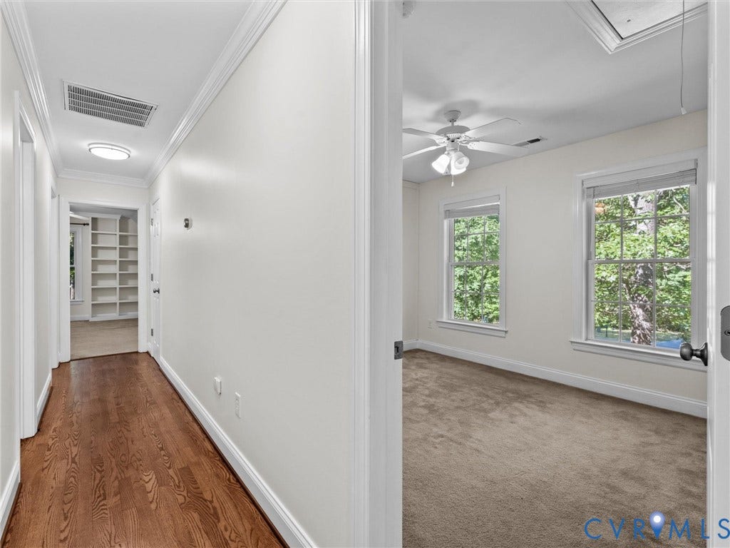 Hallway with wood-finish flooring leading to a room with built-in shelving