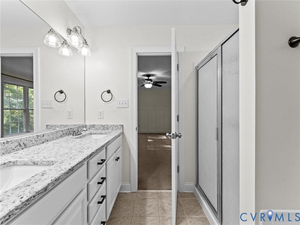 Double vanity with integrated sinks, speckled countertop, and white cabinetry