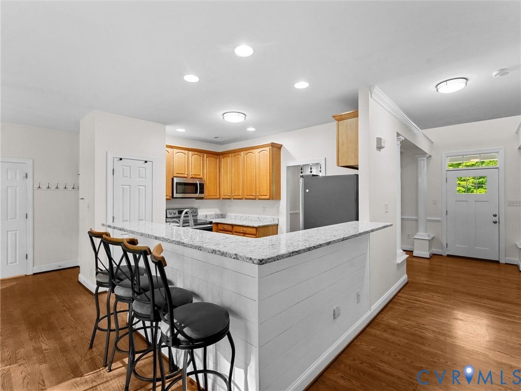 Kitchen featuring wood-finish flooring, recessed lighting, and a breakfast bar with a stone-finish countertop