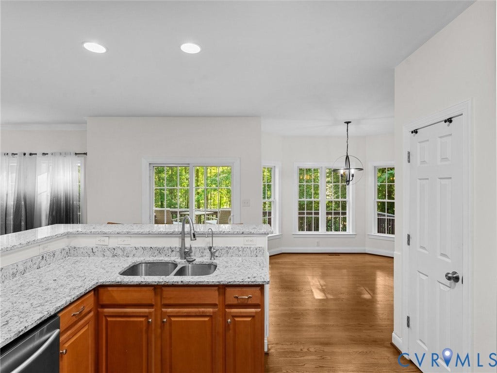 Kitchen featuring granite countertops, wood cabinetry, and a double basin sink