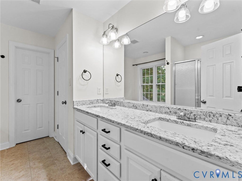 Dual vanity with white cabinetry and granite countertops