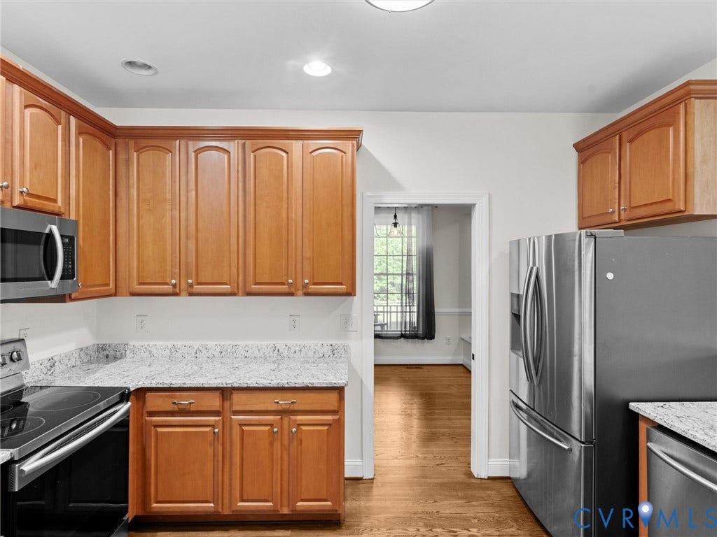 Light wood-finish cabinetry with crown molding, granite-style countertops, stainless steel appliances, and recessed lighting