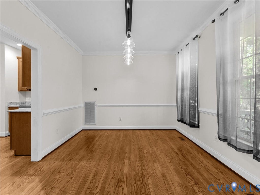 Hardwood flooring, crown molding, chair rail molding, ceiling-mounted fixture, and a window with trim