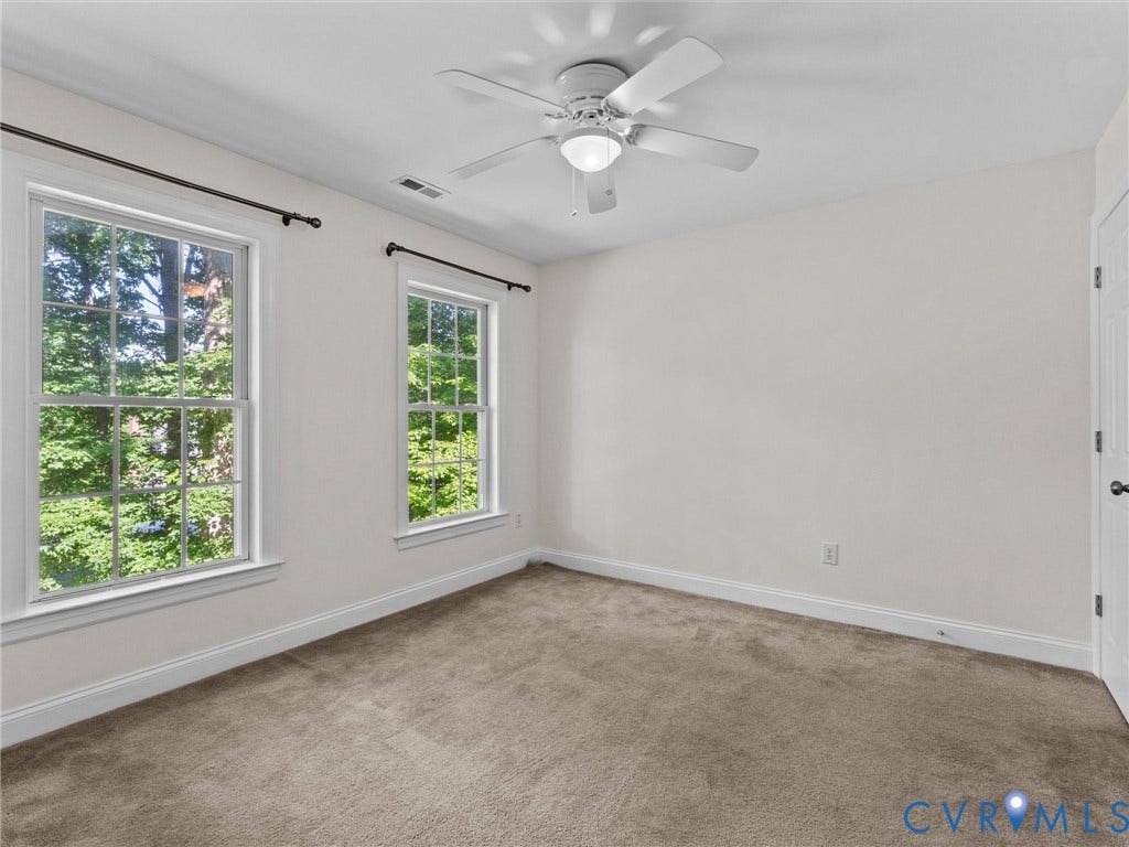 Neutral wall color, two double-hung windows, ceiling fan with integrated lighting, wall-to-wall carpeting, and white trim