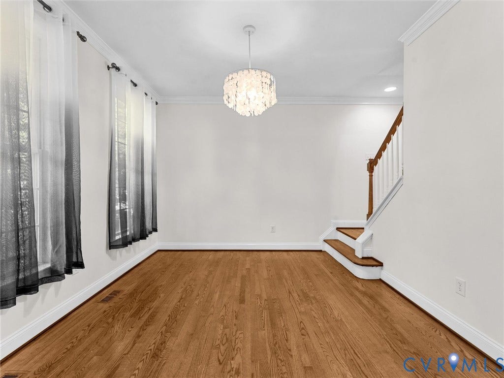 Hardwood flooring, crown molding, a decorative chandelier, and a wood staircase with white risers and balusters