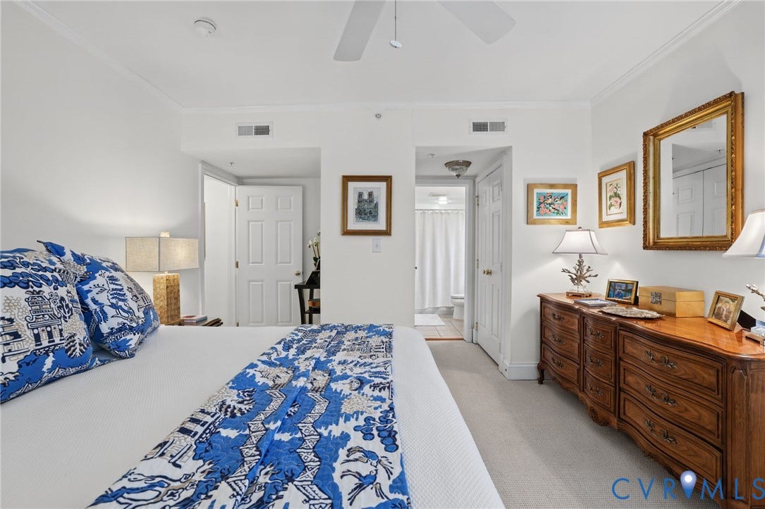 Neutral wall-to-wall carpeting, crown molding, white six-panel interior doors, and a ceiling fan
