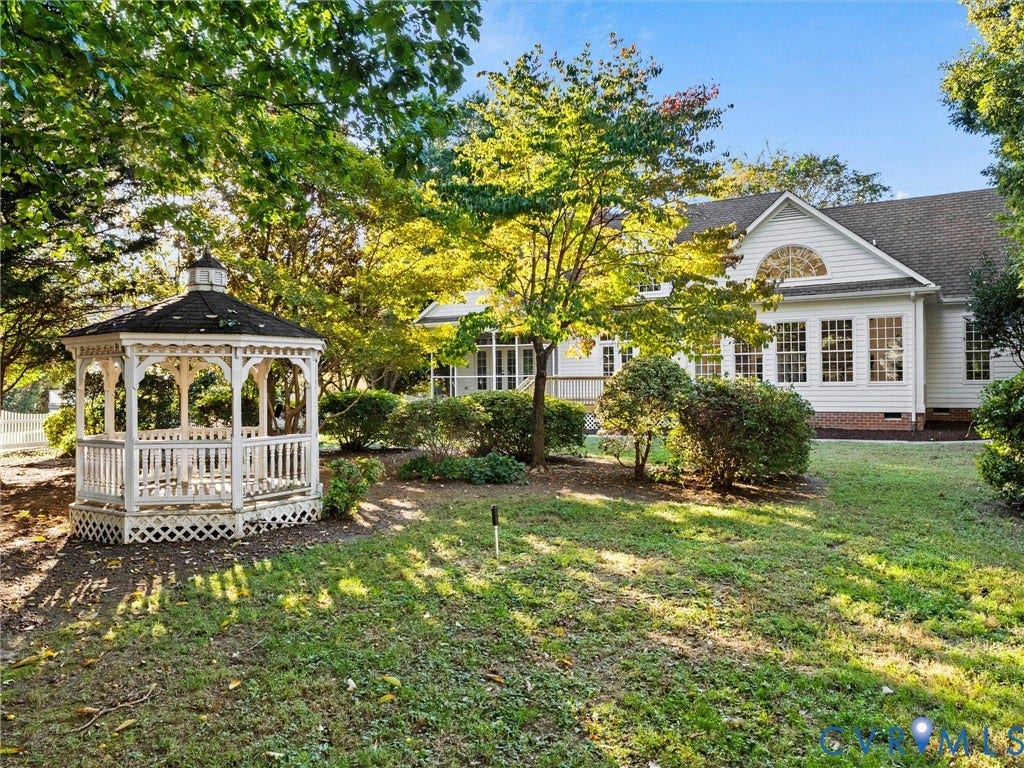 White gazebo with latticework base, expansive lawn, and mature trees