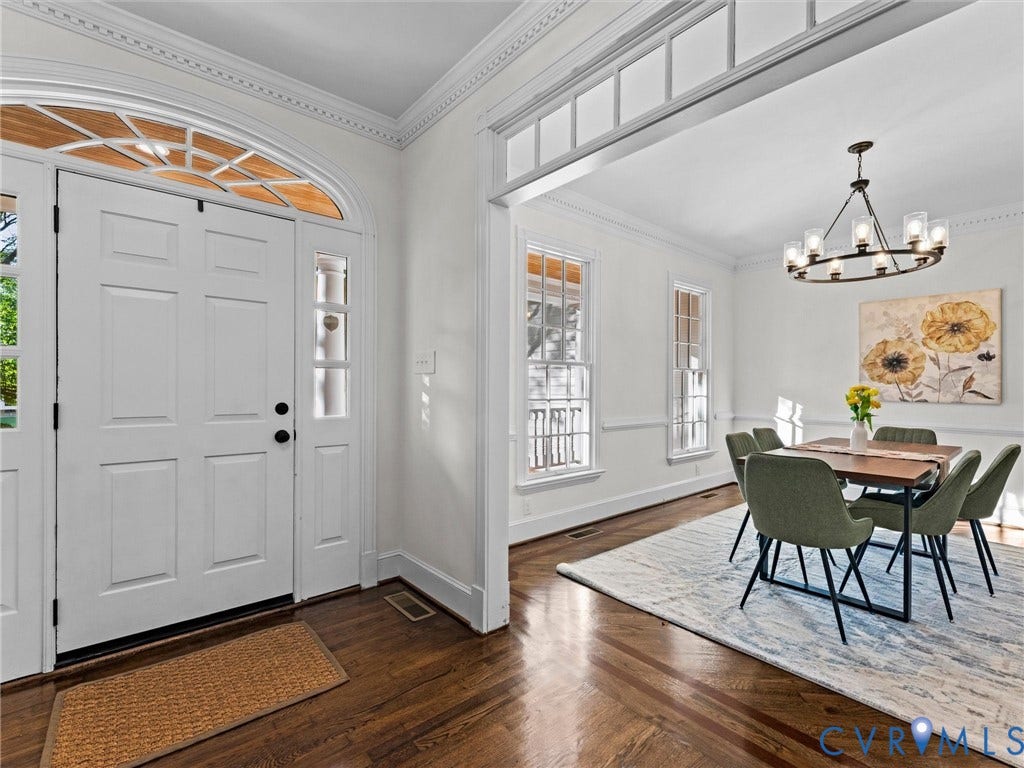 Arch-top double entry doors with sidelights, detailed crown molding, rich wood-finish flooring, and a large open doorway