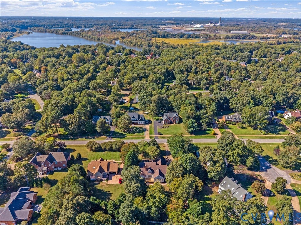 Expansive residential setting with mature trees, a visible body of water, and surrounding green spaces