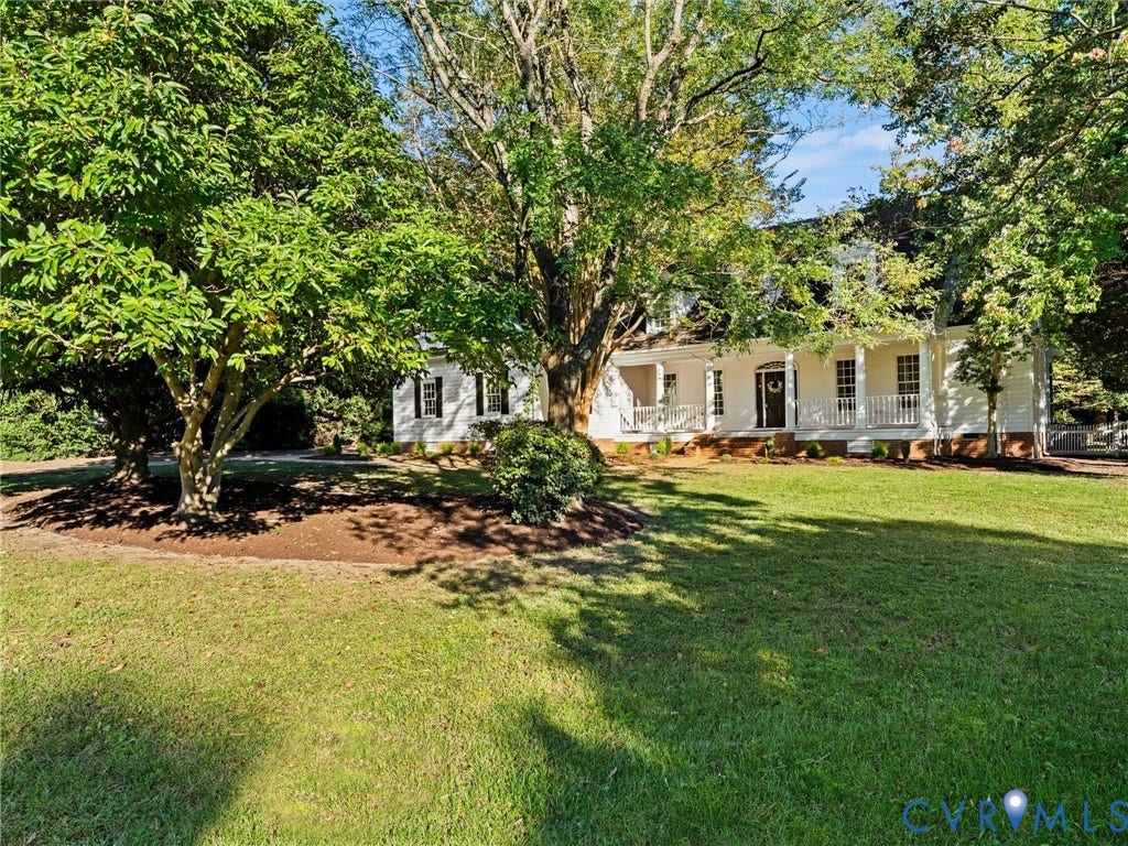 White exterior residence featuring a covered front porch with white railings, dark shutters, and a dark entry door