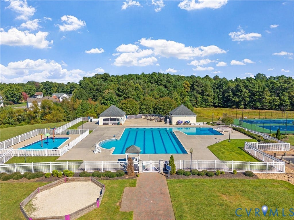 Community recreation area featuring multiple swimming pools, two tennis courts, and a sand pit