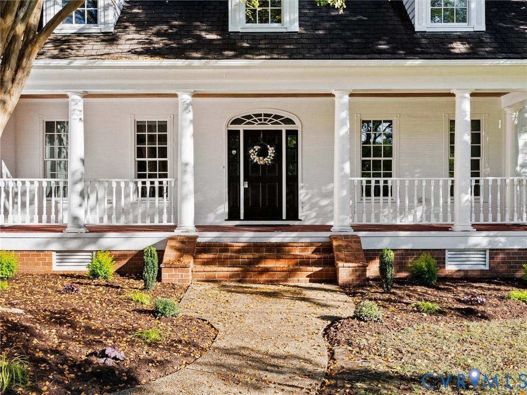 White faade with a covered porch featuring white columns and balusters