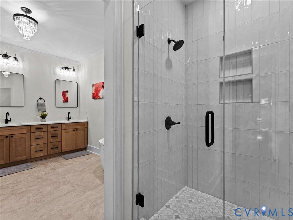 Walk-in shower with vertical subway tile, glass enclosure, and geometric floor tile