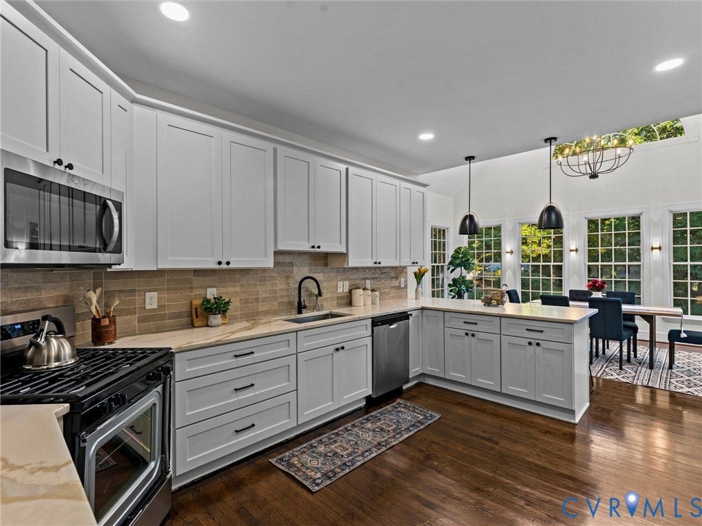 Well-appointed kitchen featuring white shaker cabinetry, stainless steel appliances, light-toned countertops, and a tile backsplash