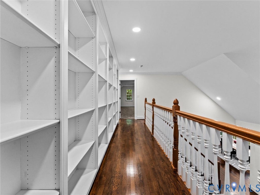 Hallway featuring extensive built-in shelving, hardwood flooring, and recessed lighting