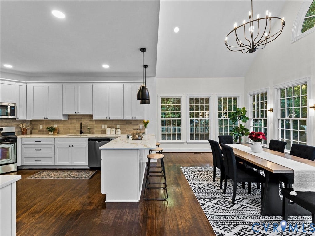 White shaker cabinetry with dark hardware, stone-finish countertops, wood-finish flooring, and vaulted ceiling
