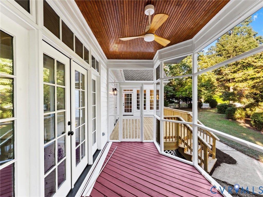 Screened porch featuring a wood-finish ceiling with ceiling fan, French doors with multiple panes, white painted trim and railings, burgundy composite decking, and expansive views of mature landscaping and green lawn