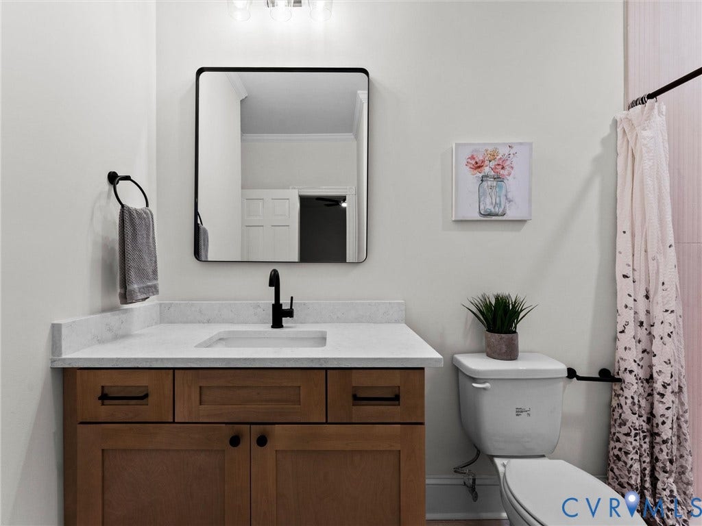 Wood-finish vanity with an integrated sink, light-toned countertop, and matte black hardware